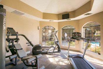 a gym with exercise equipment and a pool in the background